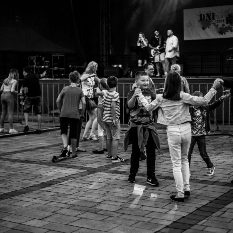 Czarno-białe zdjęcie ludzi tańczących pod sceną.