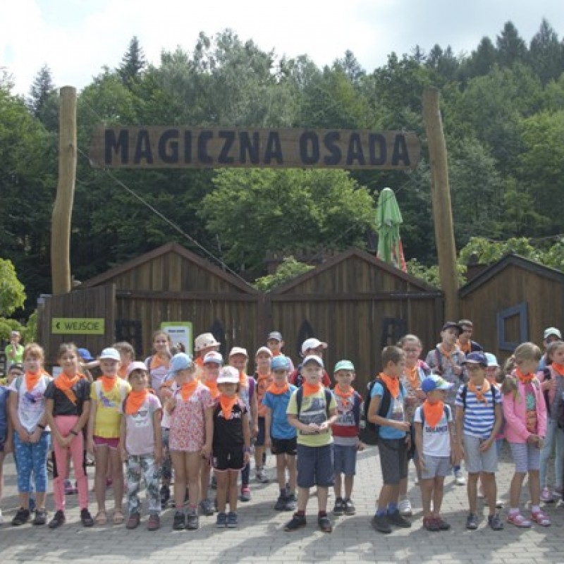 Dzieci pozują do zdjęcia w grupie przed wejściem do "Magicznej osady".