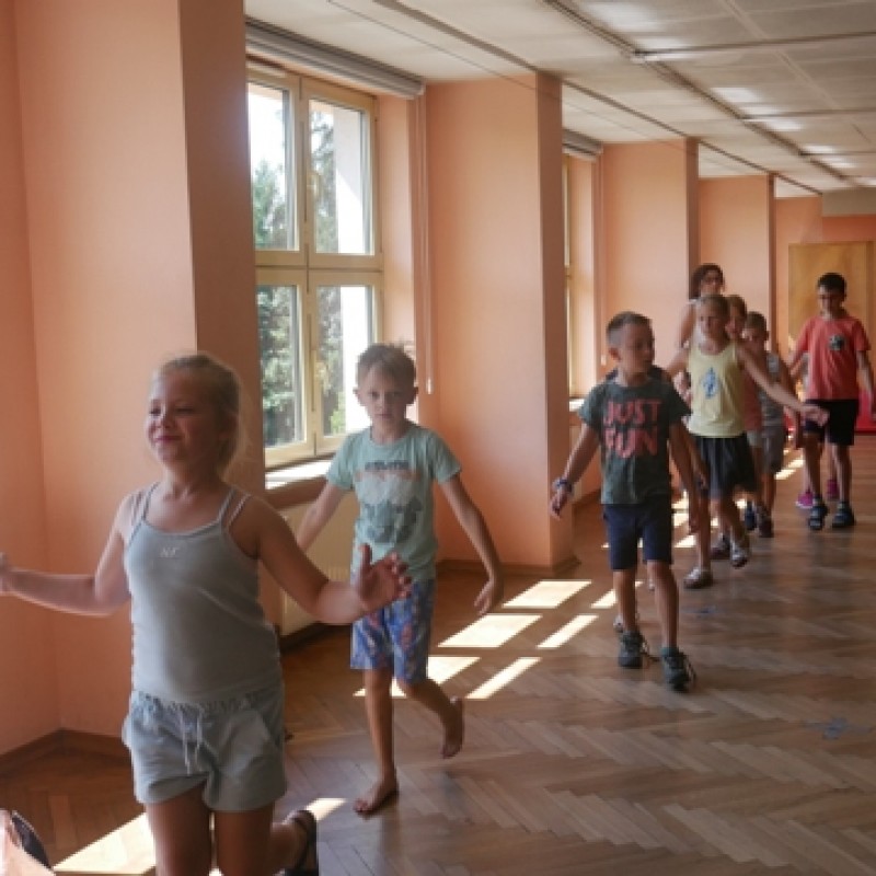 dzieci w rzędzie są w ruchu podczas zajęć na sali z lustrami.