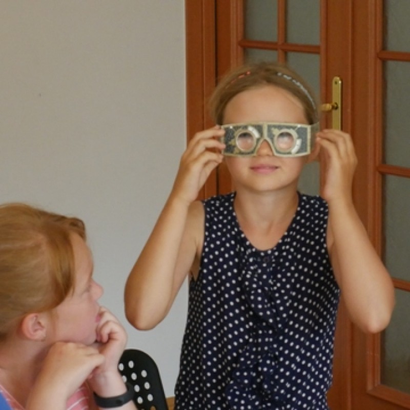 Dziewczynka pozuje do zdjęcia przykładając rękoma zrobione okularki.