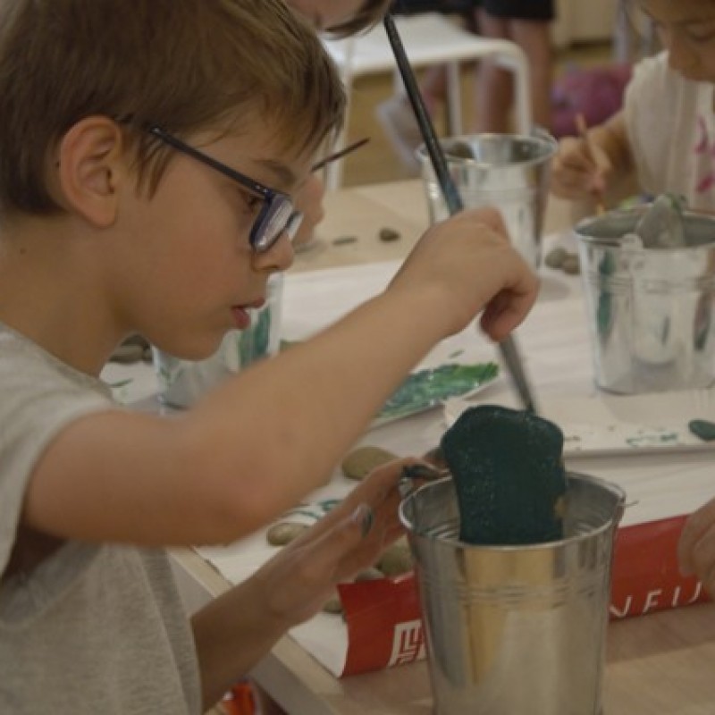 Chłopiec wykonuje kaktusa na zajęciach plastycznych malując kamienie.