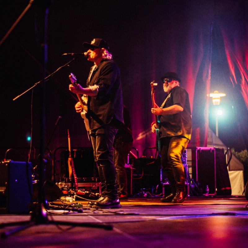 Zespół muzyczny podczas występu na scenie w świetle wielobarwnych reflektorów.
