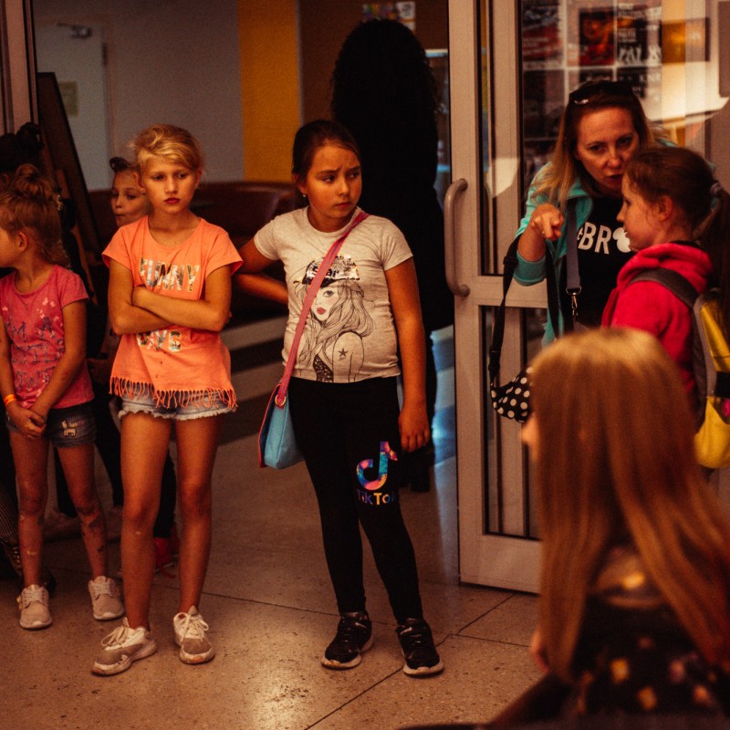 Grupa dzieci w obecności dorosłych stoi w galerii Domu Kultury.