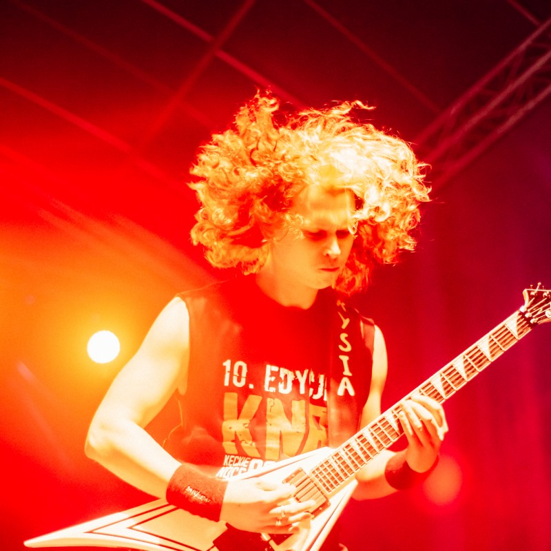 Gitarzysta podczas występu na scenie w czerwonym świetle reflektorów.