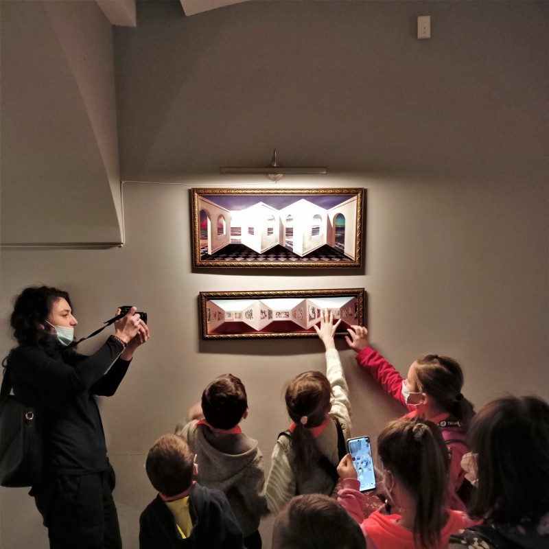 Dzieci eksplorują wystawę dotykając eksponatu pani prowadząca robi im zdjęcie.