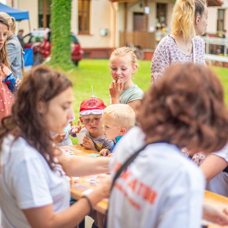 Fot. Łukasz Kuc/Dzieci i dorośli zgromadzeni są wokół stołu na którym są przedmioty do wykonywania zmywalnych tatuaży.