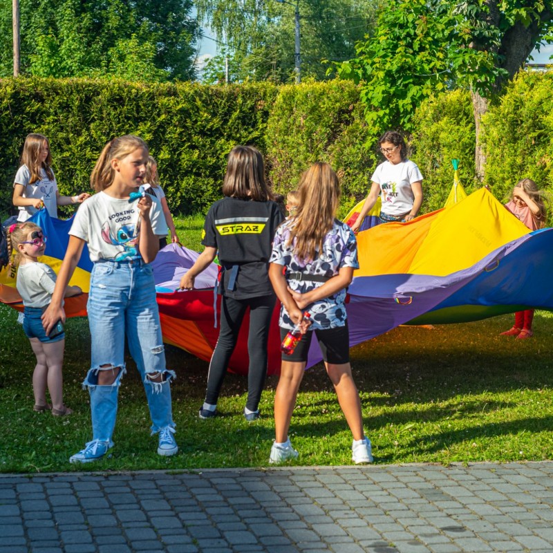 Fot. Łukasz Kuc/Dzieci bawią się na świeżym powietrzu chustą Klanzy w słoneczny dzień.