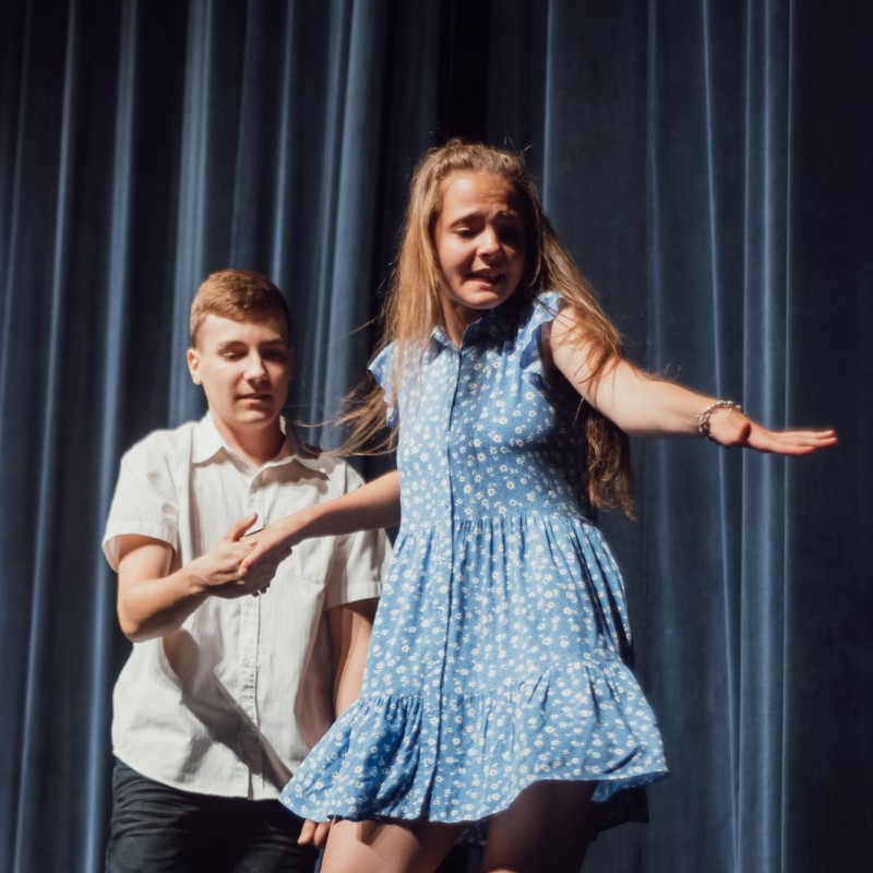 Fot. Łukasz Kuc/Chłopiec i dziewczyna tańczą na scenie domu kultury, trzymają się za ręce. 