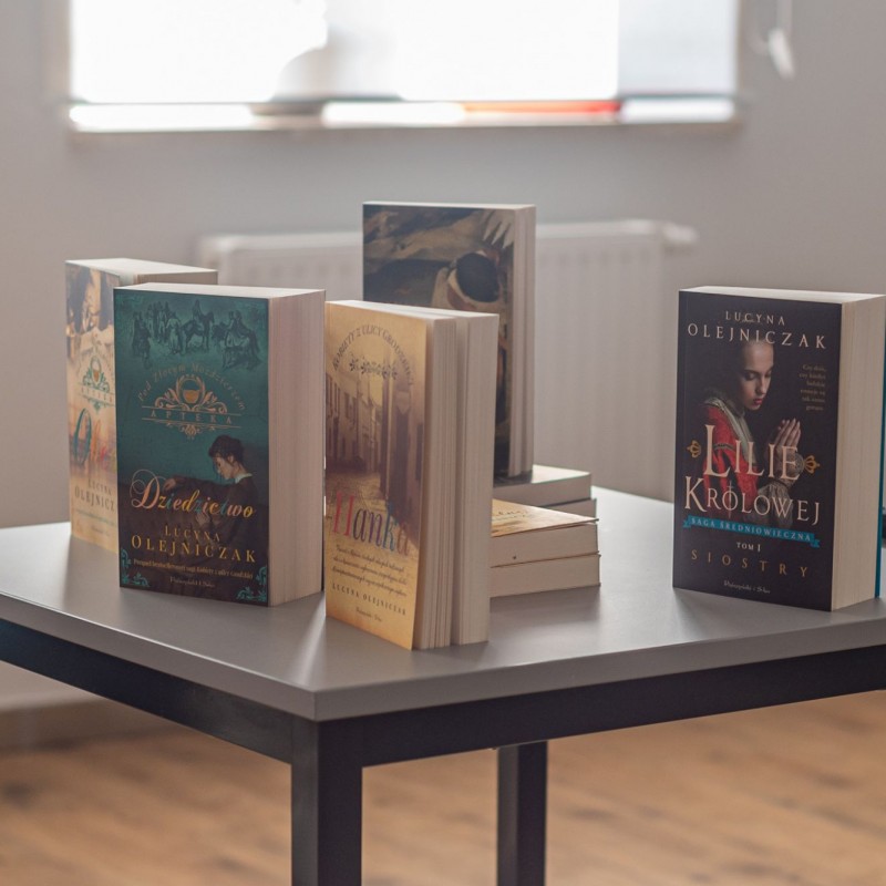 Fot. Łukasz Kuc/Kilka książek leży na szarym, kwadratowym stole.