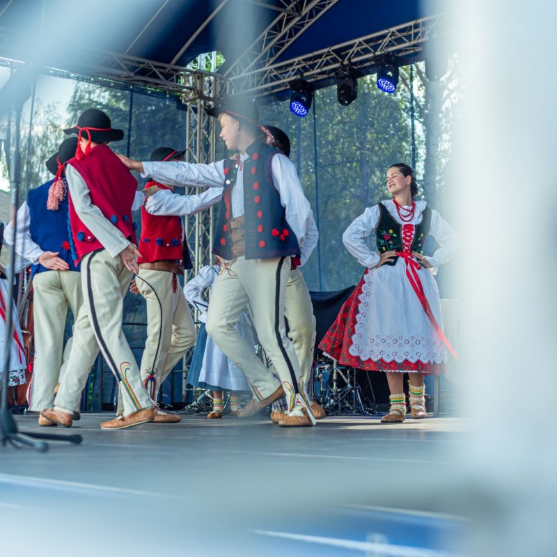 Fot. Łukasz Kuc/Starsza grupa osób ubranych w regionalne stroje tańczy na scenie plenerowej.