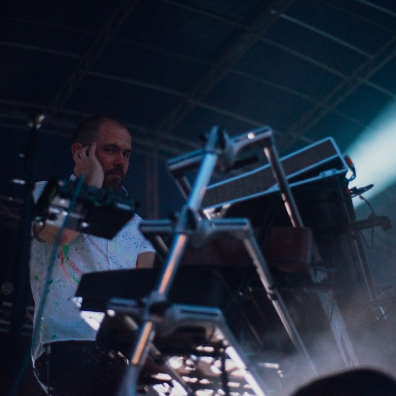 Fot. Łukasz Kuc/Członek zespołu podczas występu trzymający rękę przy twarzy kryjacy się za keyboardami.